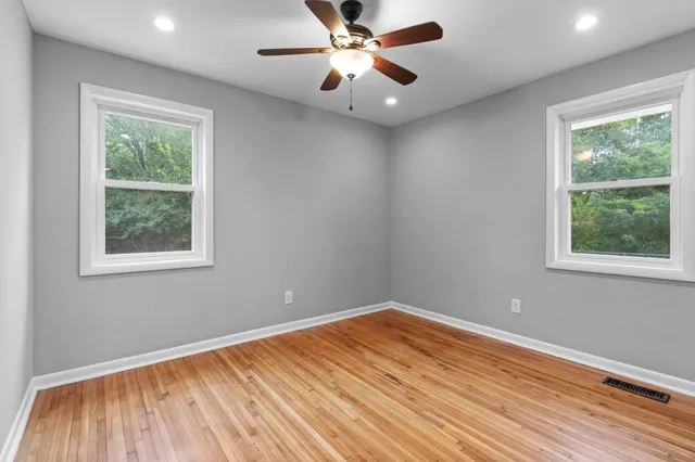 a view of empty room with wooden floor and fan