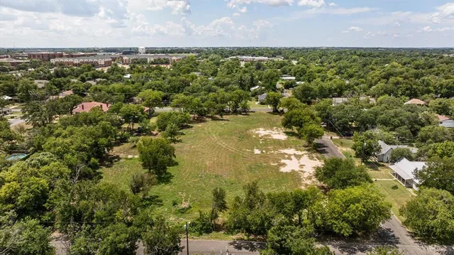 an aerial view of residential houses with outdoor space and trees