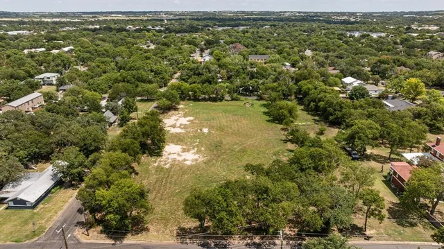 an aerial view of residential houses with outdoor space and trees
