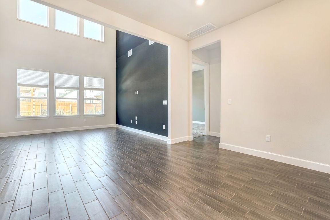 4705 Sea Salt Drive Austin, TX 78747 - Photo 5 of 19 Spare room featuring plenty of natural light, wood finish floors, and a towering ceiling