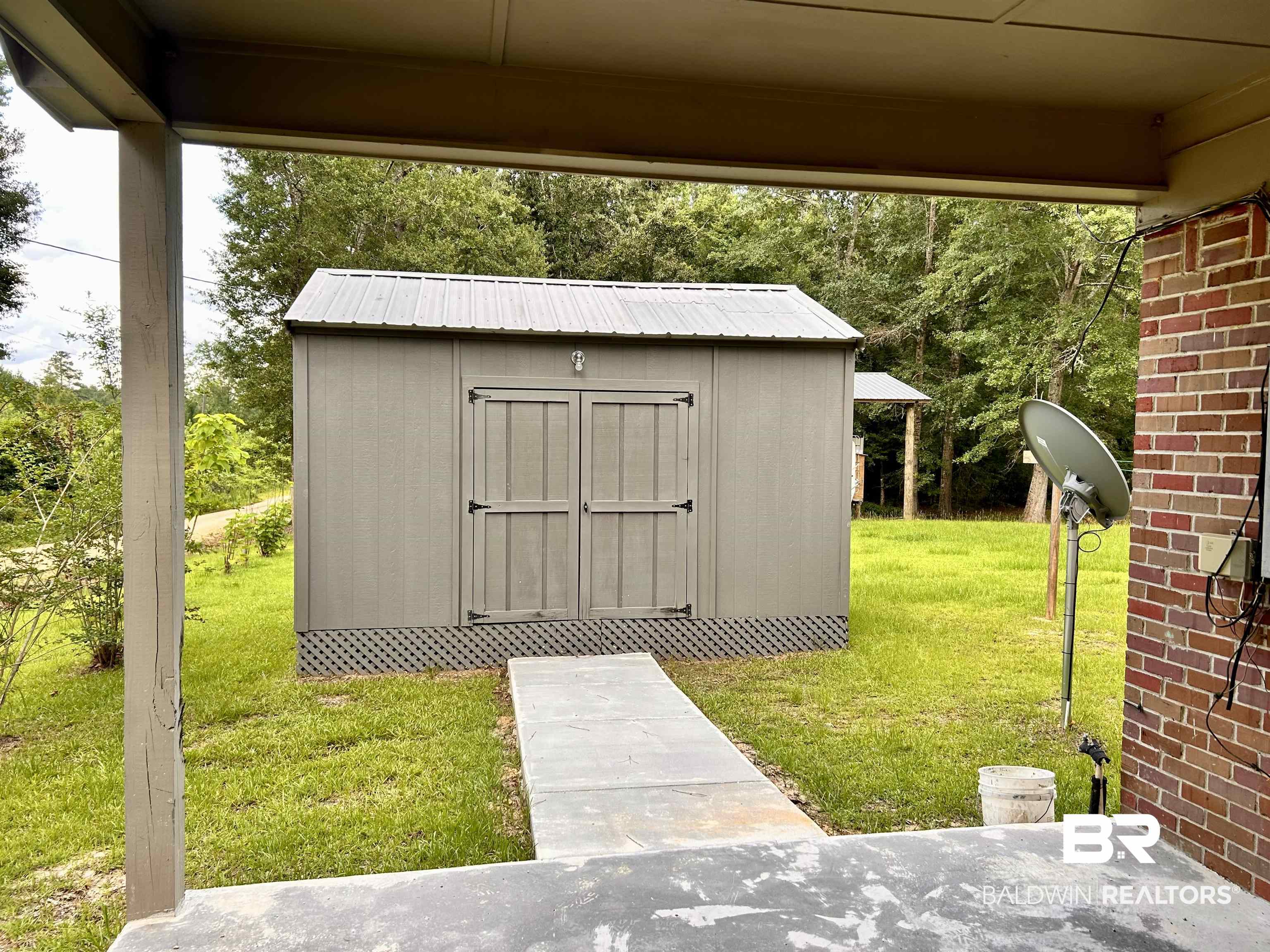 7870 Bradley Road Brewton, AL 36426 - Photo 8 of 8 Detached storage shed with a metal roof and double doors, positioned on a concrete pad