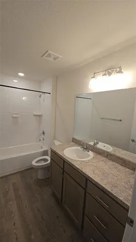 a bathroom with a granite countertop sink a toilet and shower