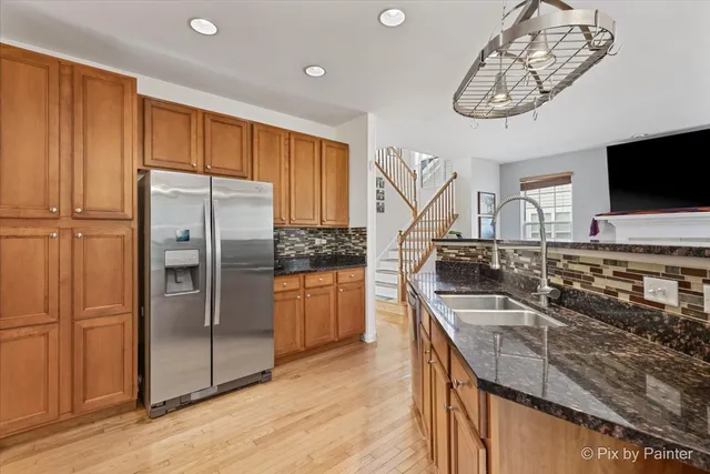 a kitchen with stainless steel appliances granite countertop a refrigerator a stove and a sink with wooden floor