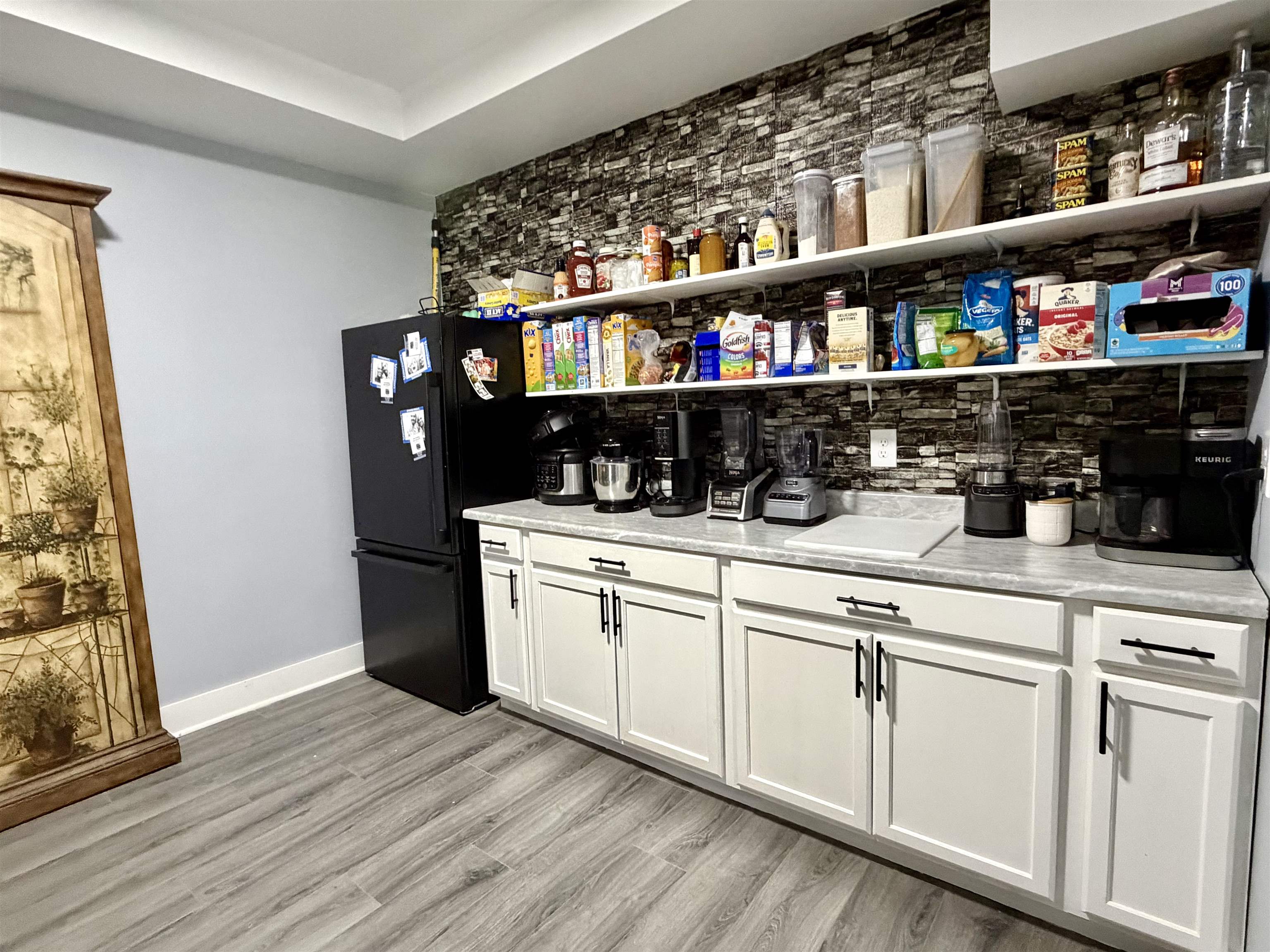 3670 Peavine Road Middleton, TN 38052 - Photo 15 of 36 Kitchenette or pantry area featuring wood-finish flooring, a black refrigerator, white shaker-style base cabinetry with matte black hardware, and light-toned countertops
