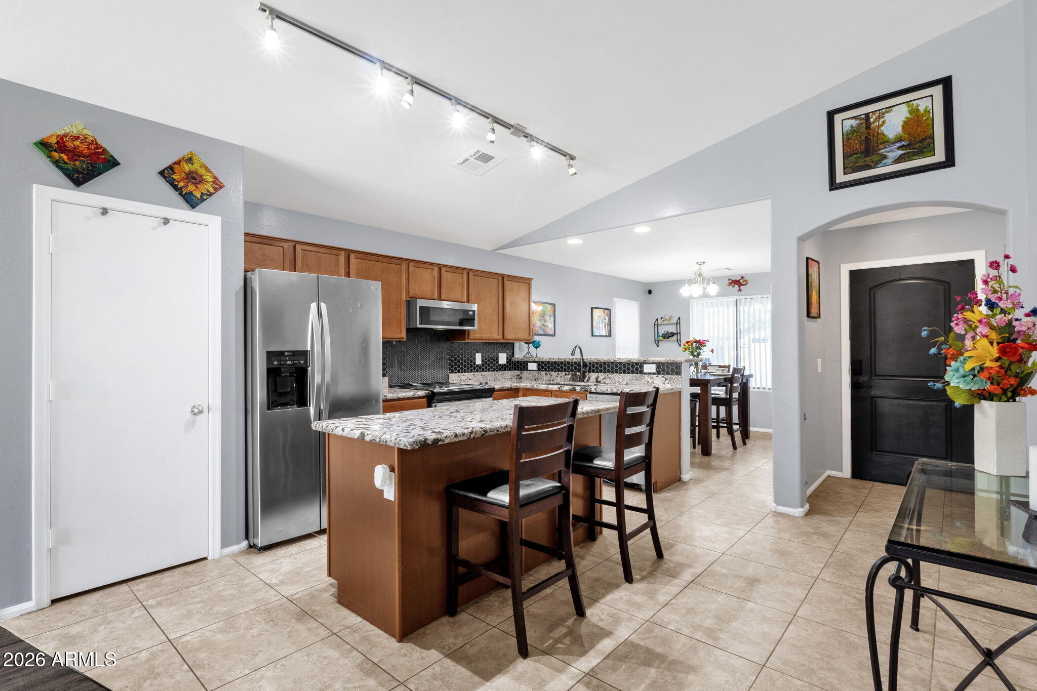 4629 West Carson Road Laveen, AZ 85339 - Photo 11 of 37 a kitchen with stainless steel appliances kitchen island granite countertop a refrigerator a stove a microwave oven a dining table and chairs with wooden floor
