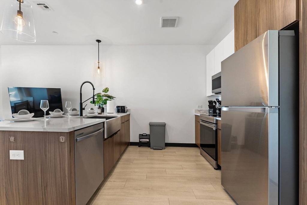 600 Broadway, Unit 608 Chelsea, MA 02150 - Photo 3 of 32 a kitchen with a sink stainless steel appliances and cabinets