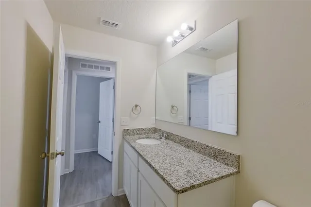 a bathroom with a granite countertop sink and a mirror