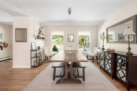 a view of a dining room and livingroom with furniture wooden floor a rug and a chandelier