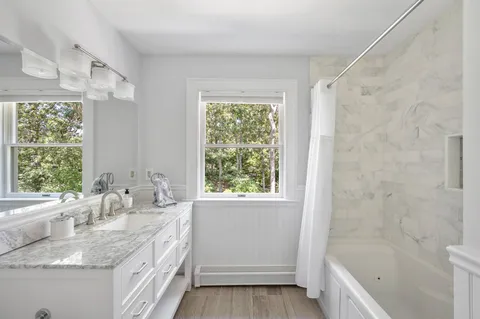 a bathroom with a granite countertop sink a bathtub and window