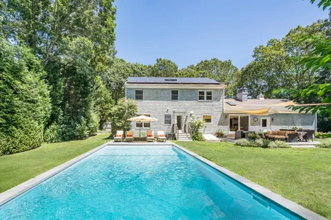 a front view of a house with garden and trees