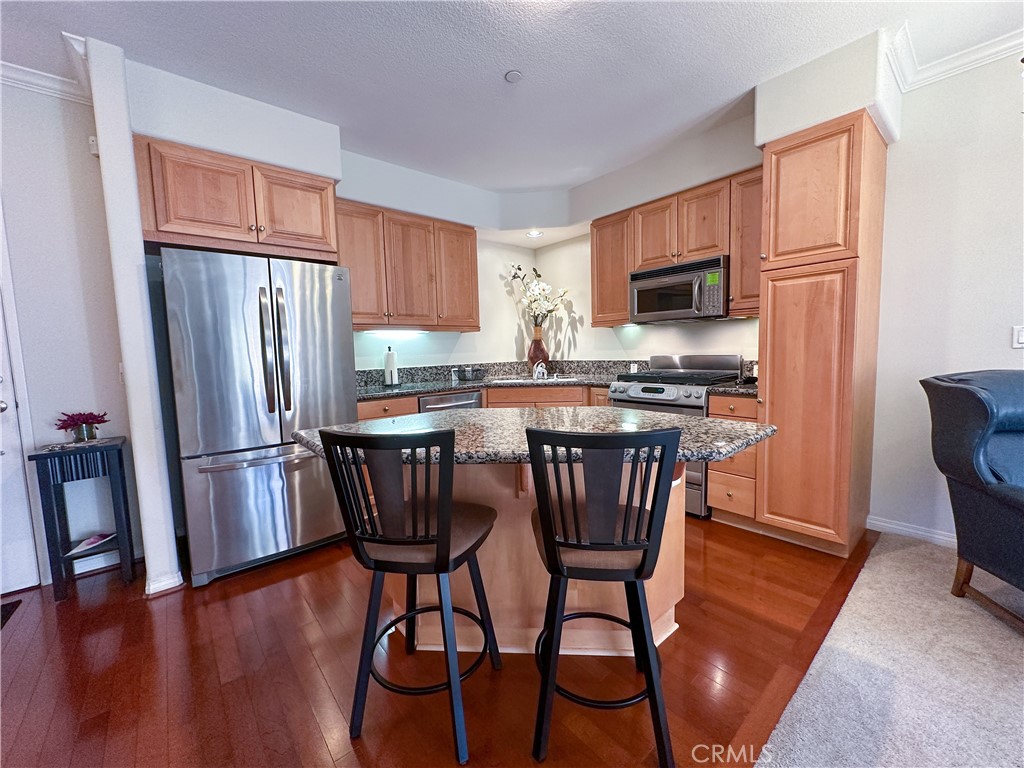 a kitchen with stainless steel appliances a microwave a stove a refrigerator a table and chairs