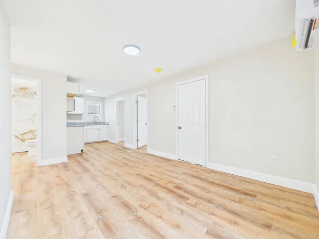 a view of a bedroom with wooden floor and a kitchen