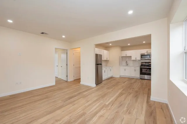 a view of a big room with wooden floor and windows