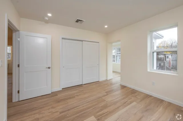 a view of an empty room with wooden floor and a window