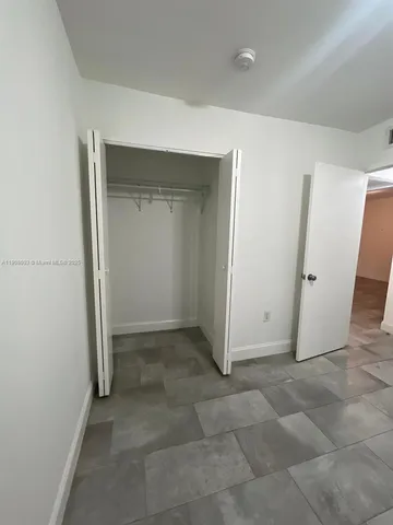 an empty room with a bench and mirror