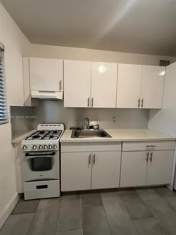 a kitchen with white cabinets and appliances