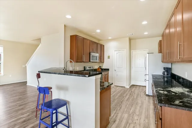 a kitchen with kitchen island granite countertop wooden floors and white cabinets