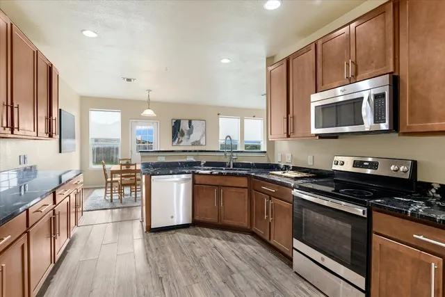 a kitchen with stainless steel appliances granite countertop wooden cabinets stove top oven and sink