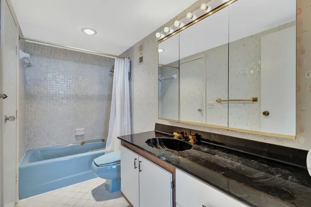 a bathroom with a granite countertop sink a toilet a mirror and bathtub