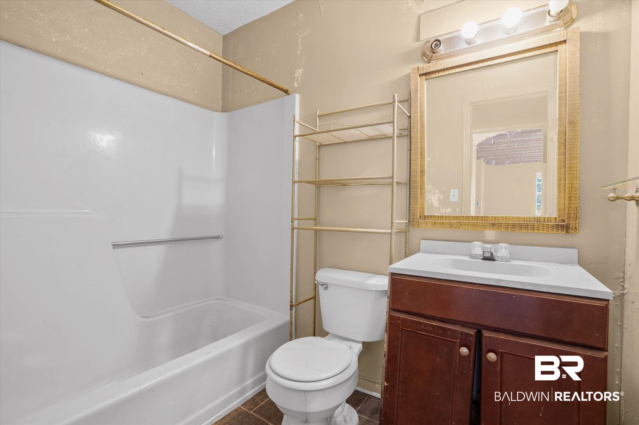 401 Frederick Avenue Fairhope, AL 36532 - Photo 17 of 36 Bathroom featuring a white tub and shower surround, a dark wood-finish vanity with an integrated sink, a mirror with a decorative frame, and a wall-mounted light fixture