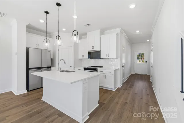 a kitchen with stainless steel appliances kitchen island a refrigerator sink and white cabinets