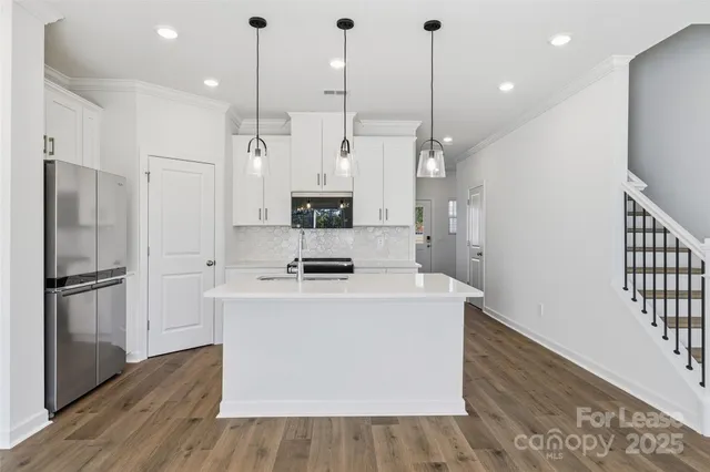a kitchen with kitchen island a sink appliances and wooden floor