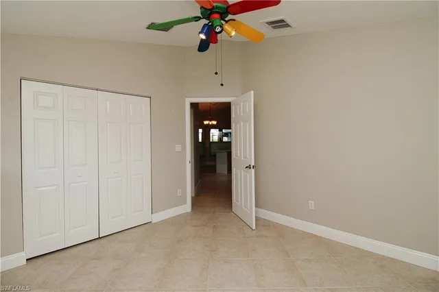 an empty room with ceiling fan and window