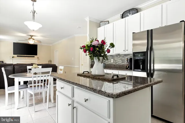 a kitchen with stainless steel appliances granite countertop a table chairs and a refrigerator