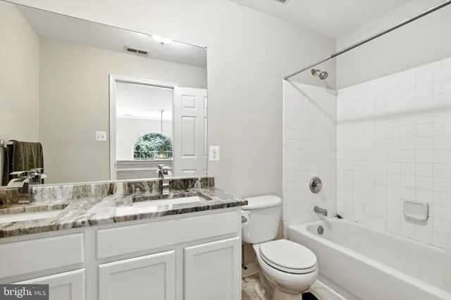 a bathroom with a granite countertop sink a toilet and shower