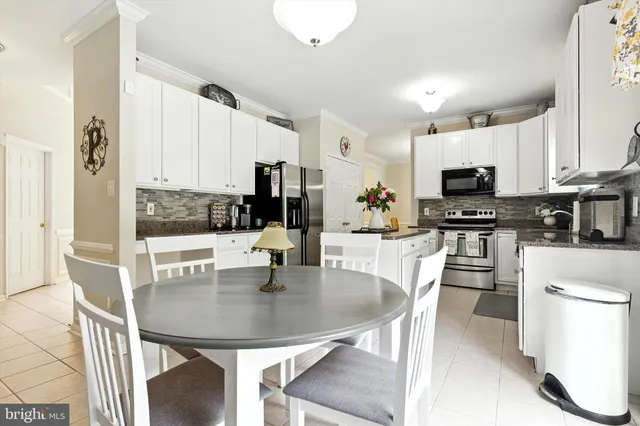 a kitchen with stainless steel appliances a dining table chairs microwave and cabinets