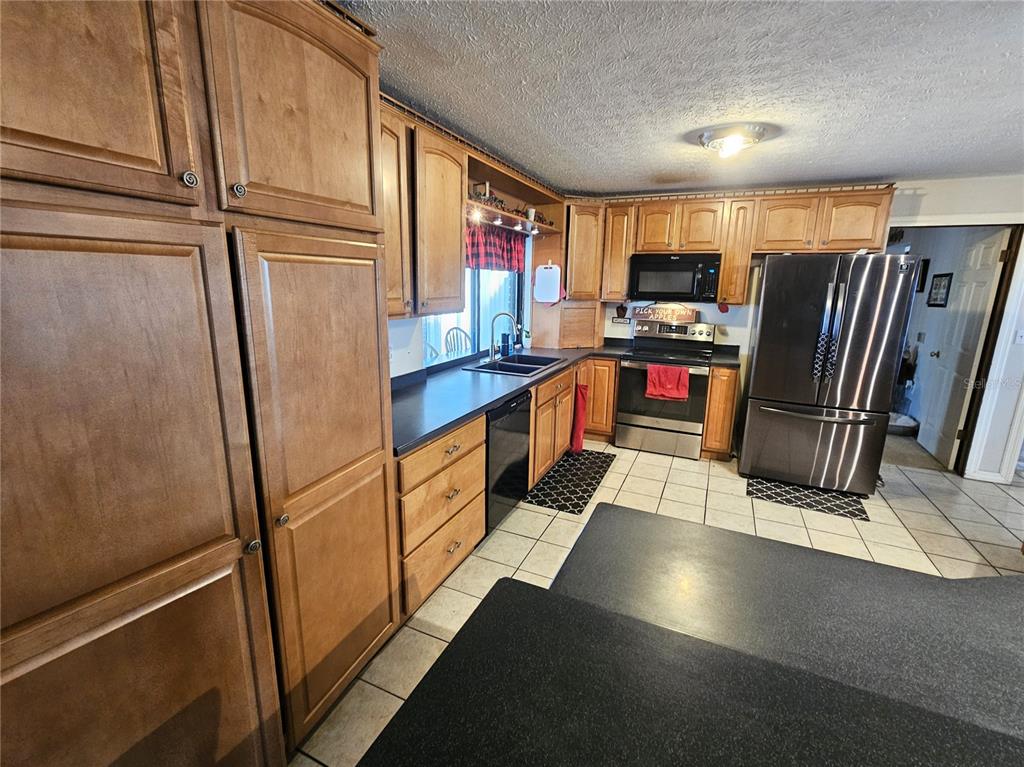 13308 Duck Lake Canal Road Dade City, FL 33525 - Photo 9 of 90 a kitchen with stainless steel appliances granite countertop a refrigerator a stove and a sink with wooden floor