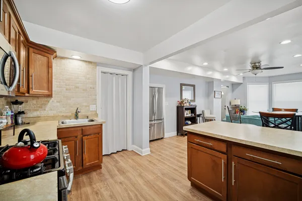 a kitchen with stainless steel appliances granite countertop a sink dishwasher and a refrigerator with wooden floor
