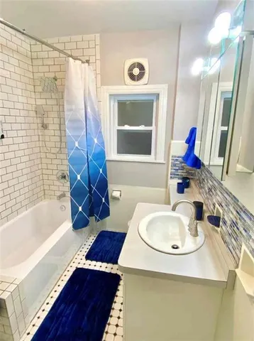a bathroom with a tub sink and mirror