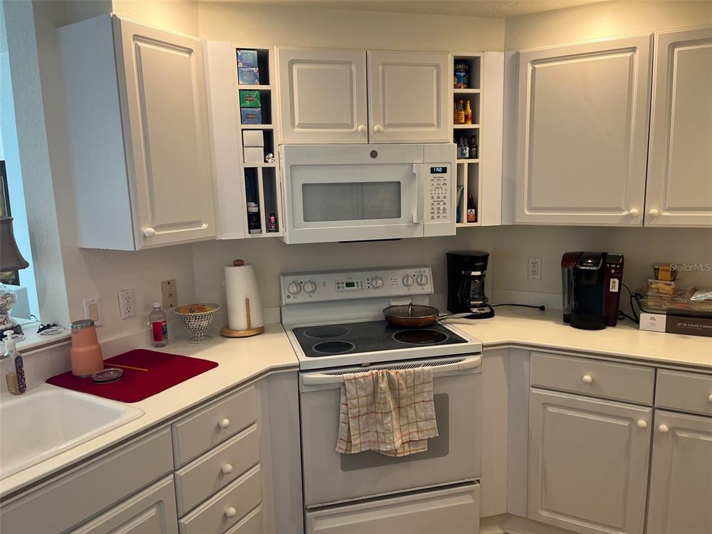 1170 Gulf Boulevard, Unit 1203 Clearwater Beach, FL 33767 - Photo 18 of 34 a kitchen with white cabinets and white appliances