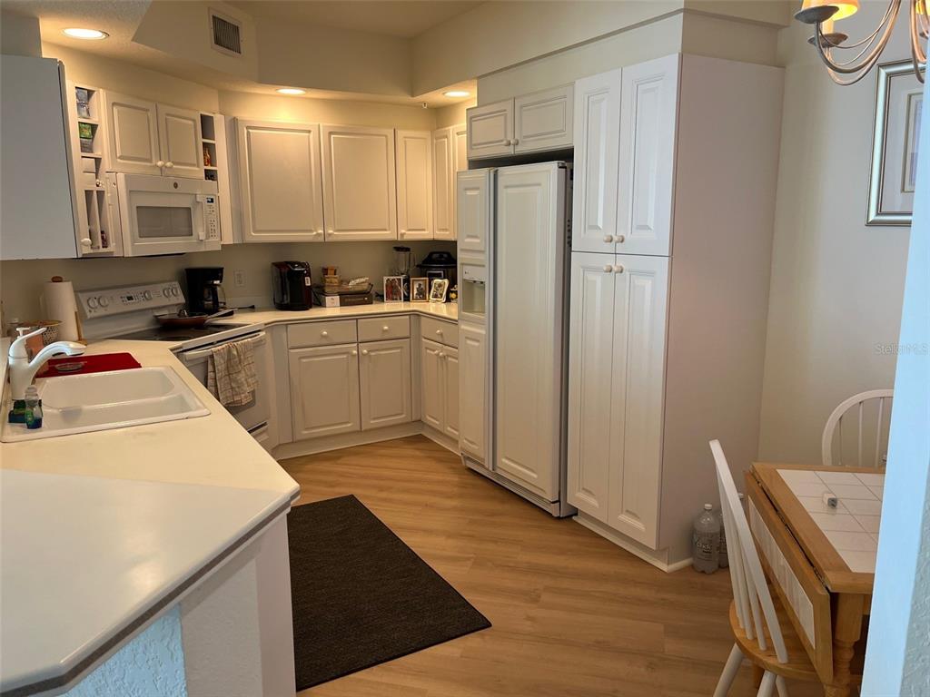 1170 Gulf Boulevard, Unit 1203 Clearwater Beach, FL 33767 - Photo 19 of 34 a kitchen with a refrigerator sink and cabinets