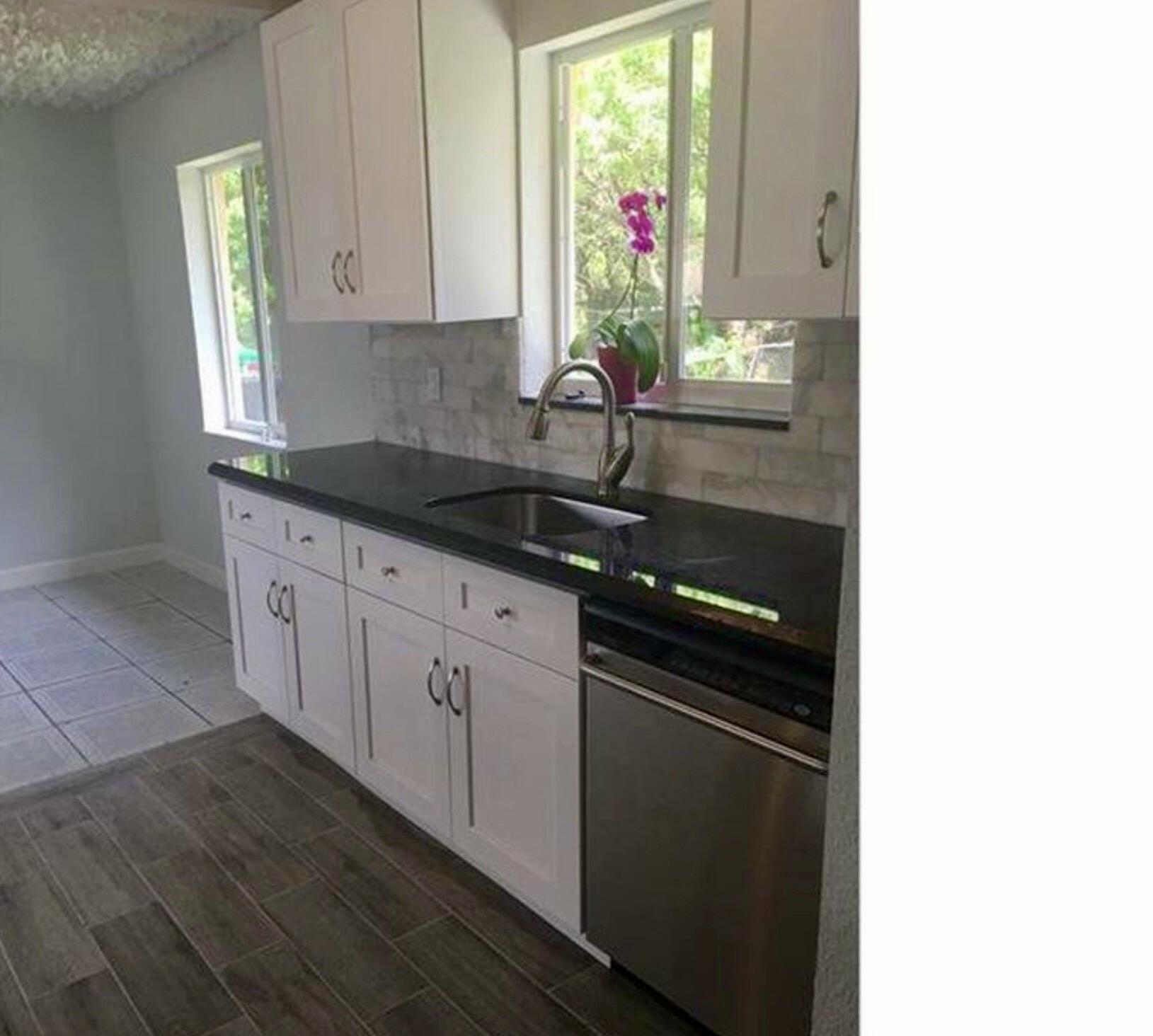 2811 Northwest 8th Street Pompano Beach, FL 33069 - Photo 3 of 7 a kitchen with granite countertop white cabinets and window