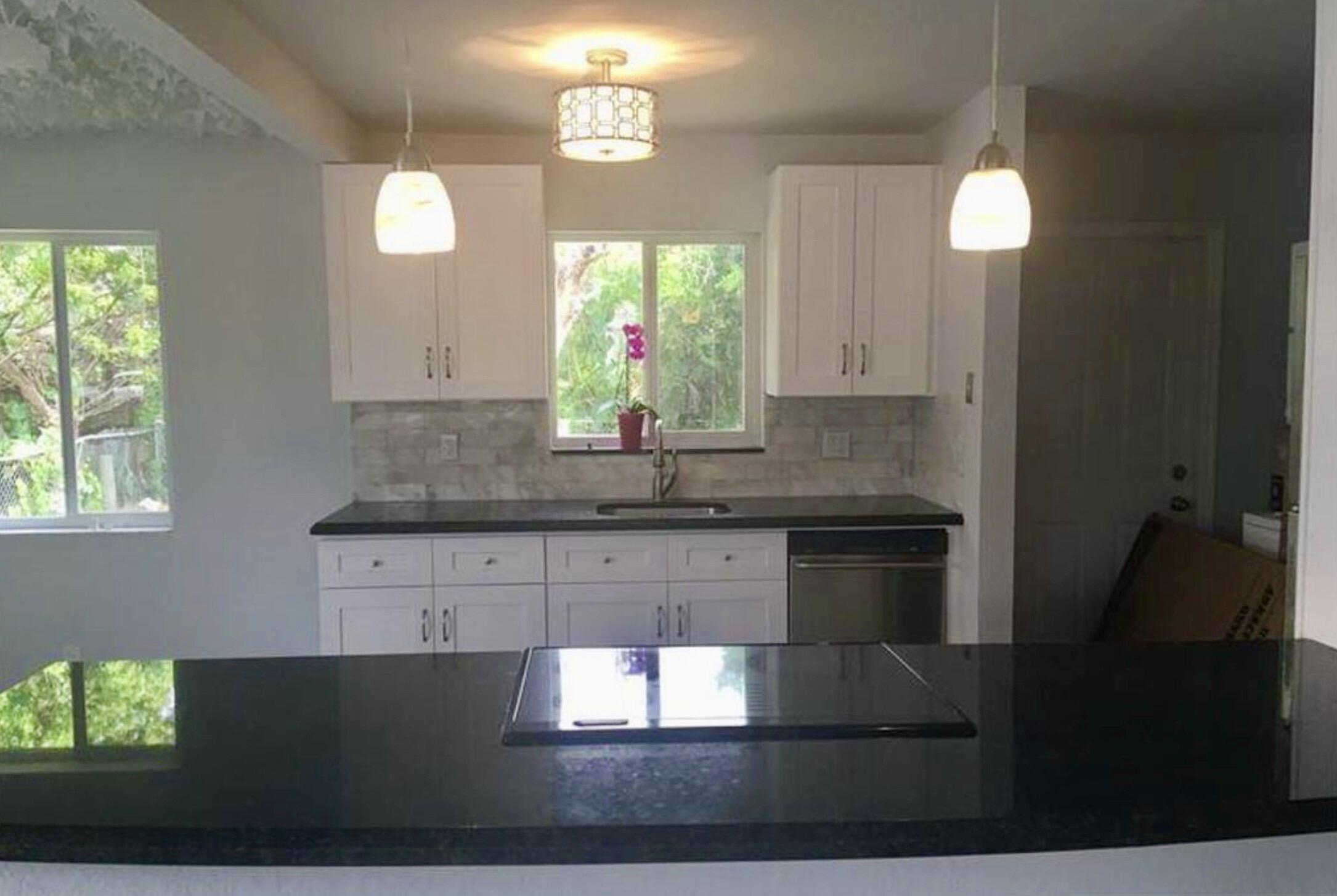 2811 Northwest 8th Street Pompano Beach, FL 33069 - Photo 4 of 7 a kitchen with granite countertop a stove a sink and a window