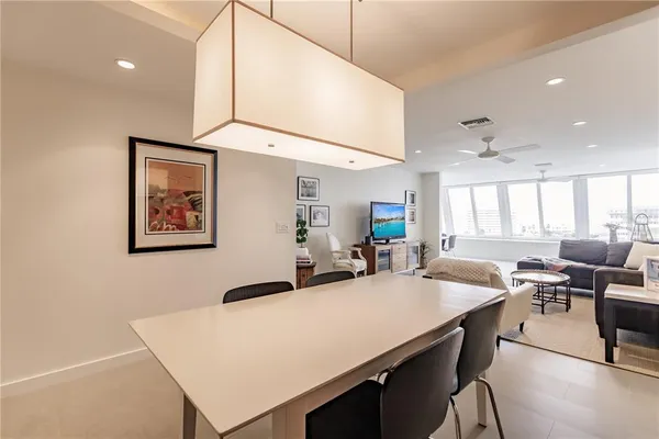 a kitchen with stainless steel appliances a stove a refrigerator a sink a dining table and chairs with wooden floor