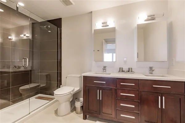 a bathroom with a toilet a sink a mirror and a shower