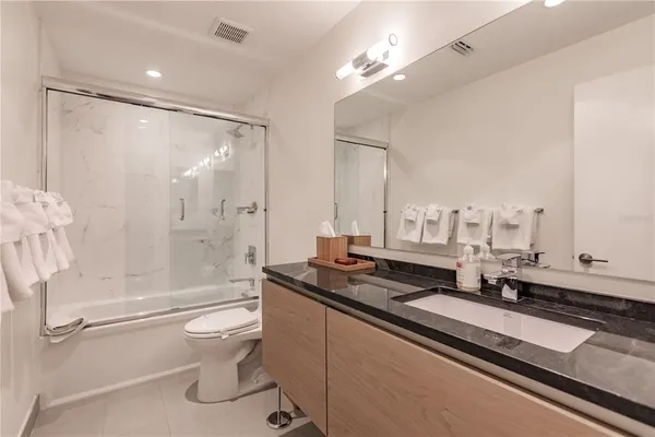 a bathroom with a granite countertop sink a toilet a mirror and shower