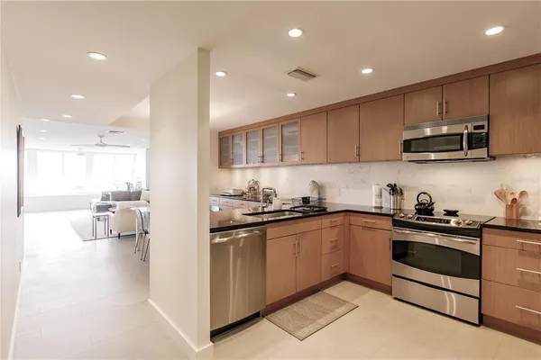 a kitchen with stainless steel appliances kitchen island granite countertop a sink and stove top oven with wooden floor