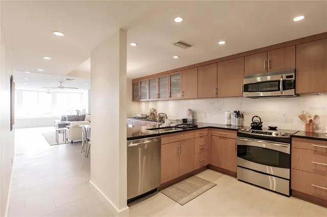 a kitchen with stainless steel appliances kitchen island granite countertop a sink and stove top oven with wooden floor