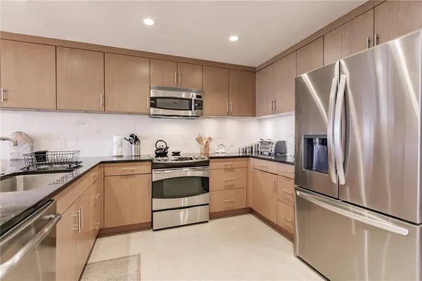 a kitchen with stainless steel appliances granite countertop a refrigerator sink and white cabinets