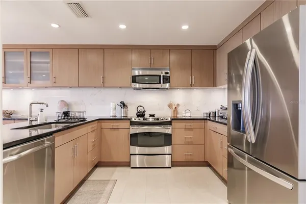 a kitchen with stainless steel appliances granite countertop a stove a refrigerator and a sink