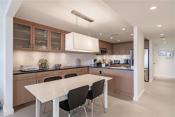 a kitchen with stainless steel appliances granite countertop a sink a stove a refrigerator and island with wooden floor