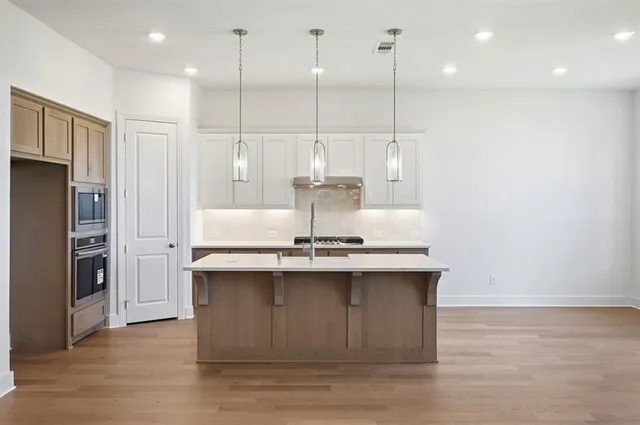 a kitchen with kitchen island a sink stainless steel appliances and cabinets