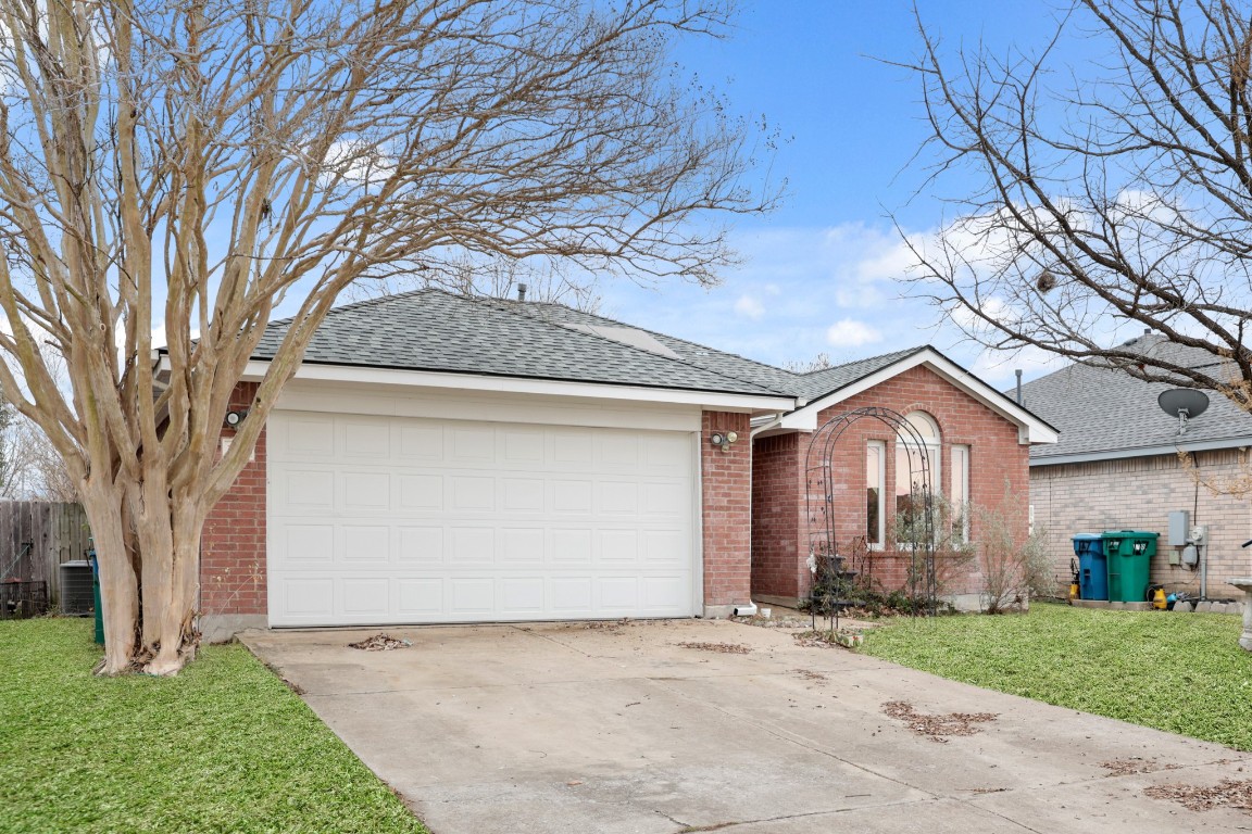 Ranch-style home with brick siding, concrete driveway, a shingled roof, and an attached garage
