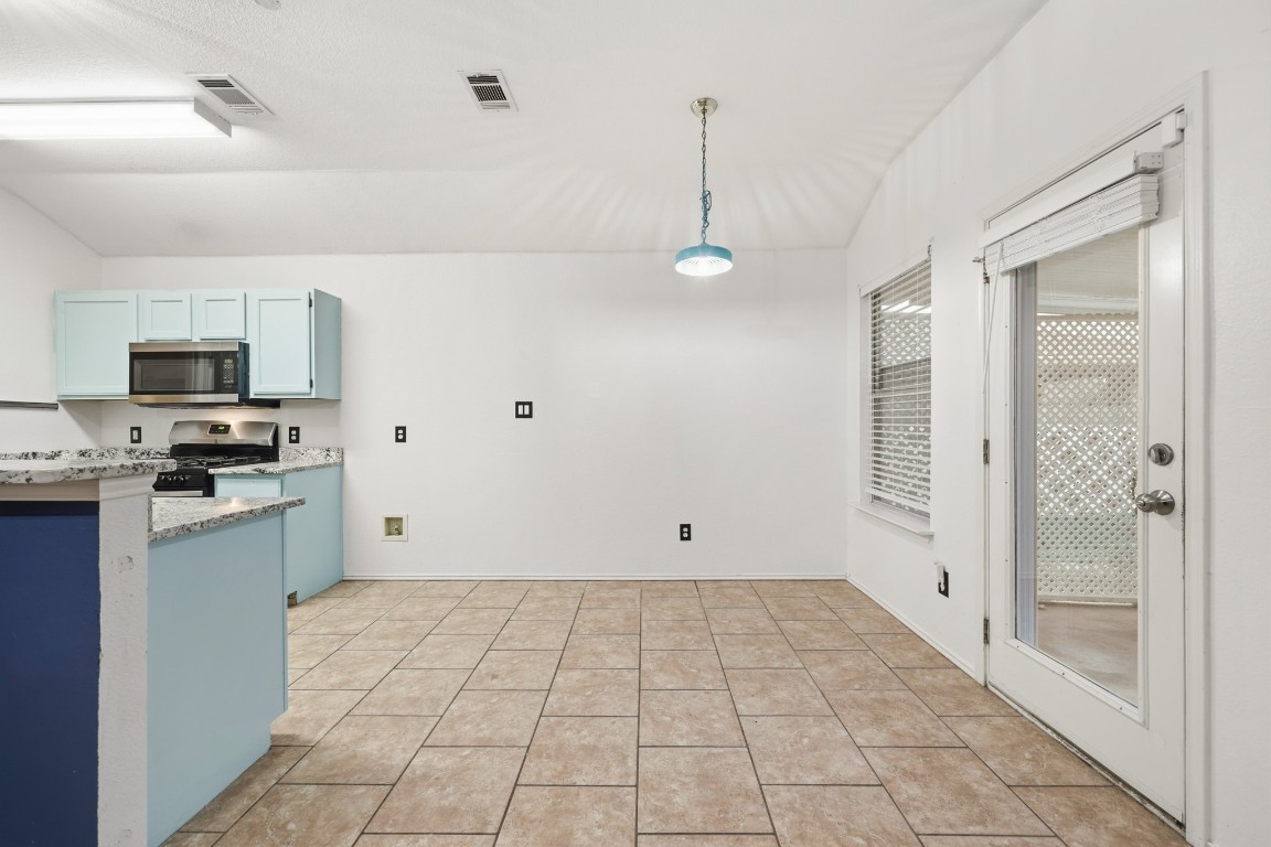 125 Blue Ridge Trail Elgin, TX 78621 - Photo 4 of 27 Updated Kitchen with pendant lighting, appliances with stainless steel finishes, lofted ceiling, light stone countertops, and light tile patterned floors