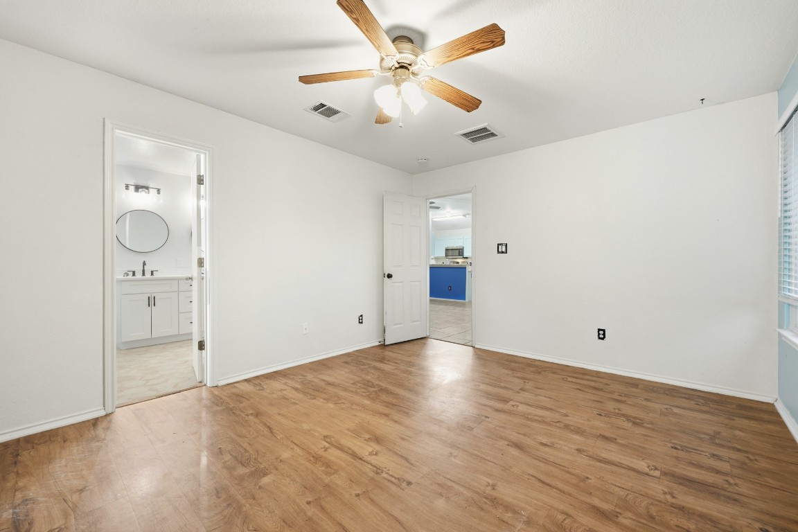 125 Blue Ridge Trail Elgin, TX 78621 - Photo 9 of 27 Unfurnished bedroom featuring wood finished floors, ceiling fan, and ensuite bathroom