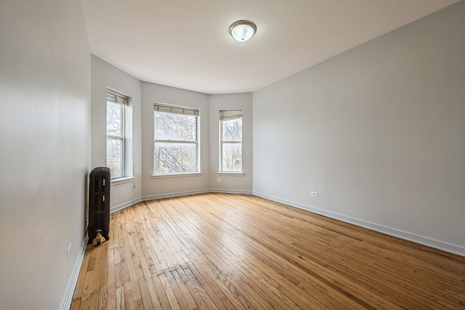 308 North Kedzie Avenue, Unit 1 Chicago, IL 60624 - Photo 4 of 11 a view of an empty room with wooden floor and a window